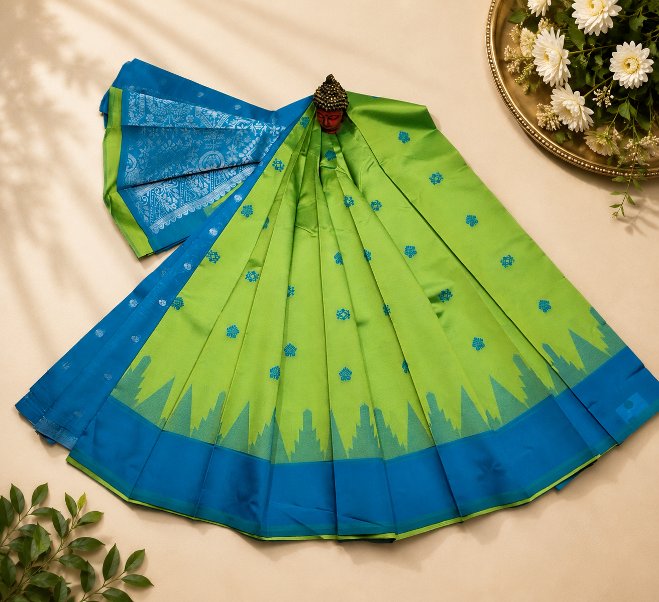 parrot green silk-cotton blend saree featuring a contrasting peacock blue zari border and intricate silver motifs across the body.
