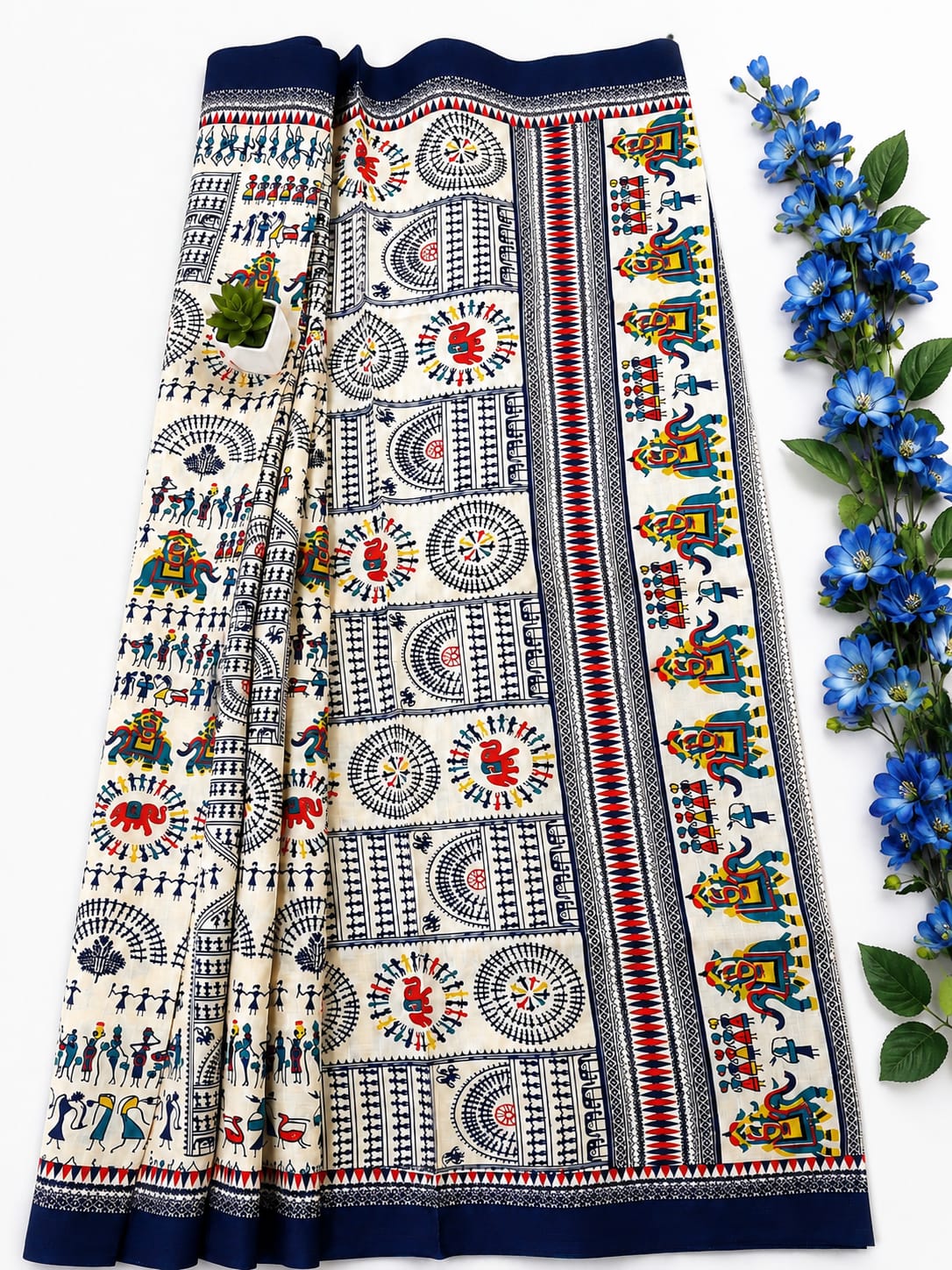 Cream and blue traditional saree features intricate Warli folk art prints, traditional geometric and tribal motifs, and a solid navy-blue border