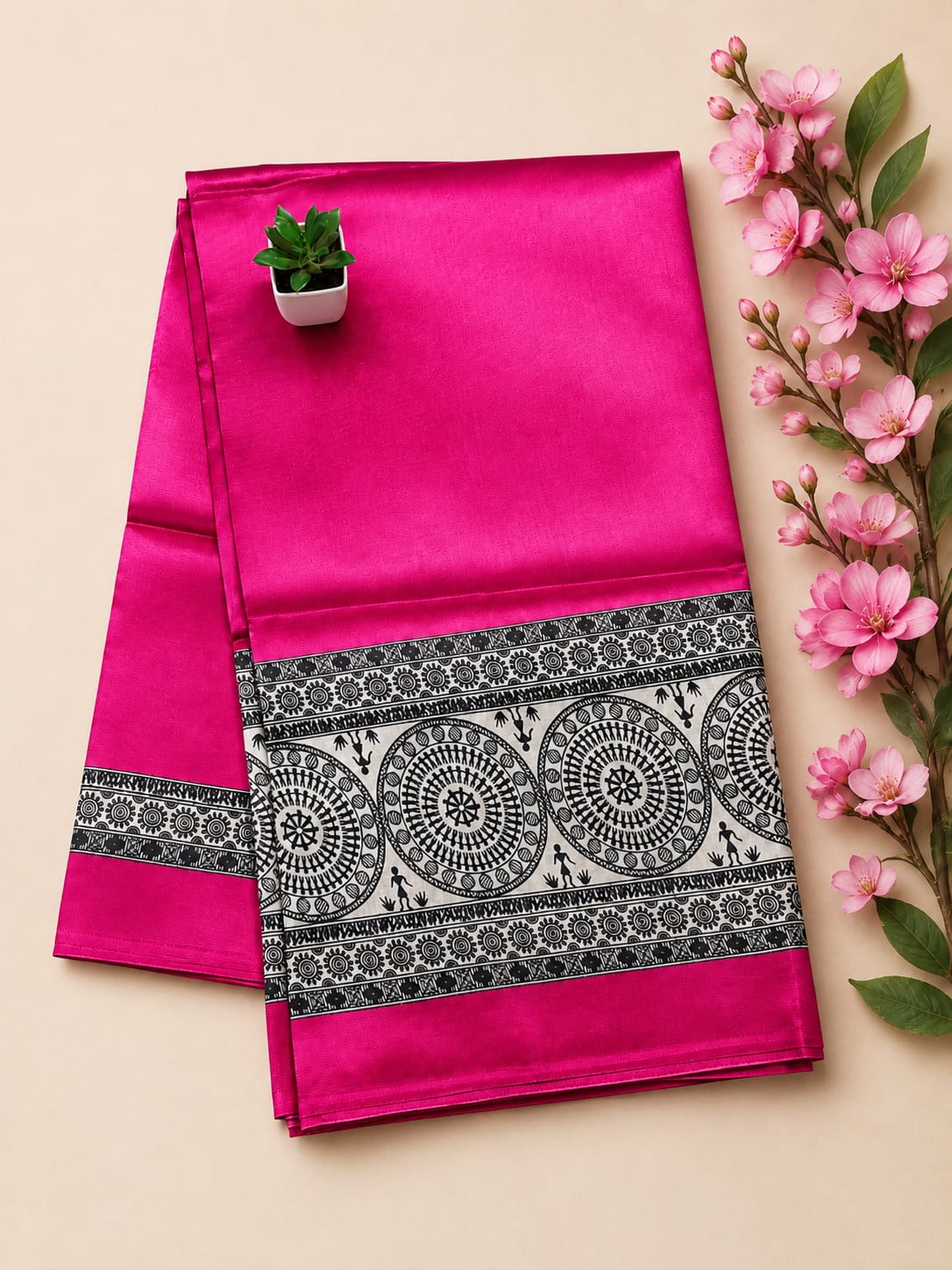 Vibrant fuchsia pink saree is beautifully detailed with a black and white Warli printed pallu and an ornate border